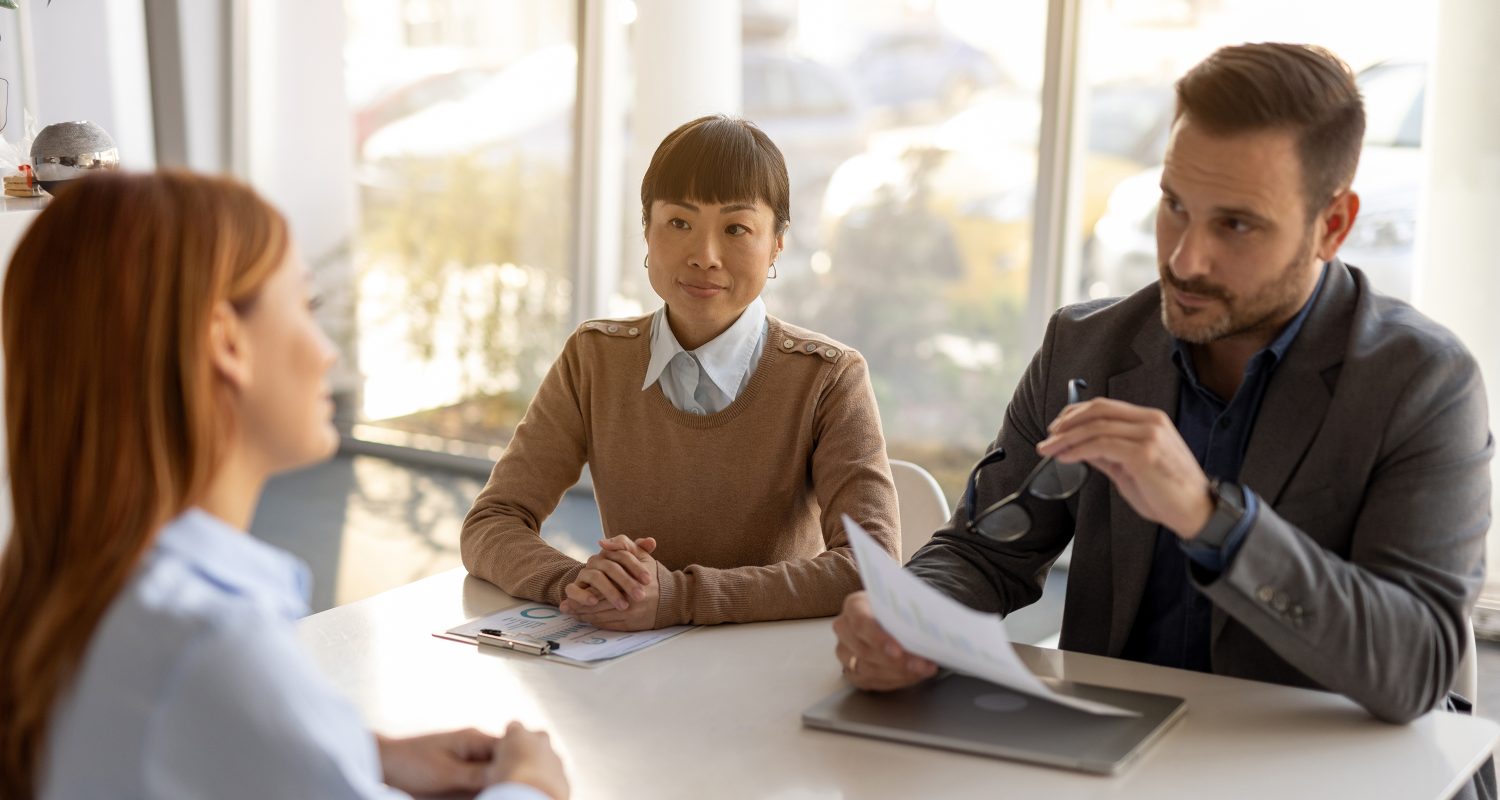 Two human resources managers. A man and a woman. Conducting an interview with a female candidate for a job position in their modern office. Engaging in thoughtful discussion and reviewing her resume