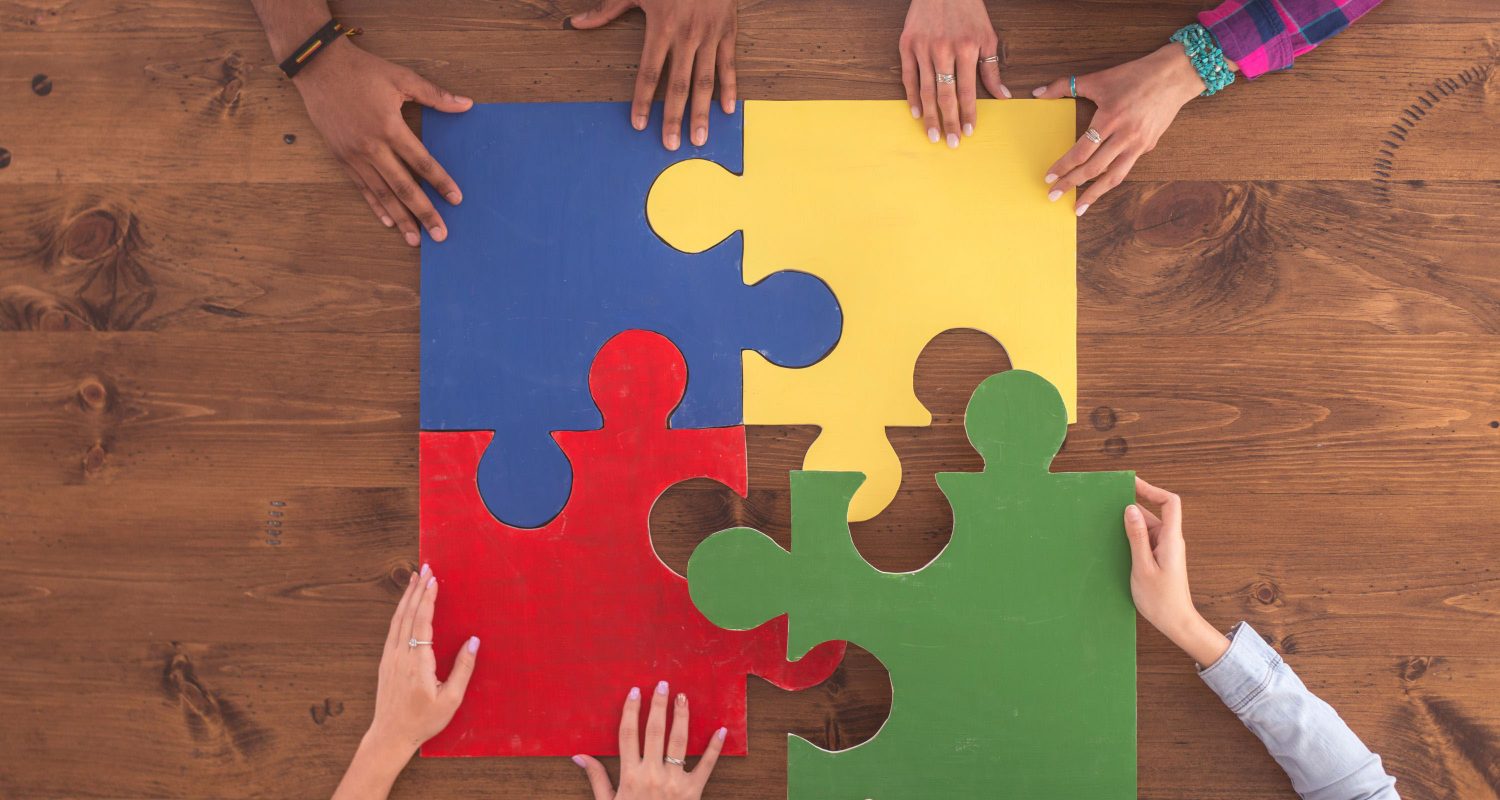 hands putting together large puzzle