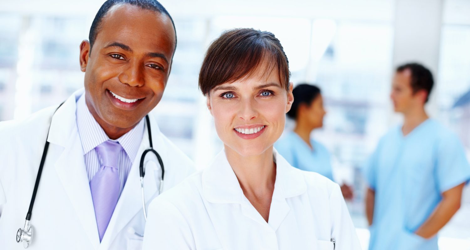 Closeup of smiling doctors with nurses in background